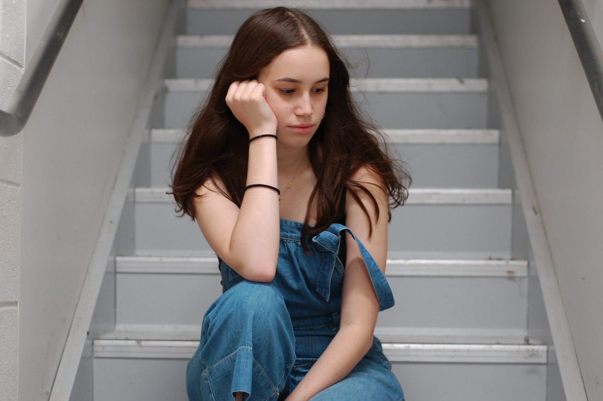 woman in blue top sitting on stairs
